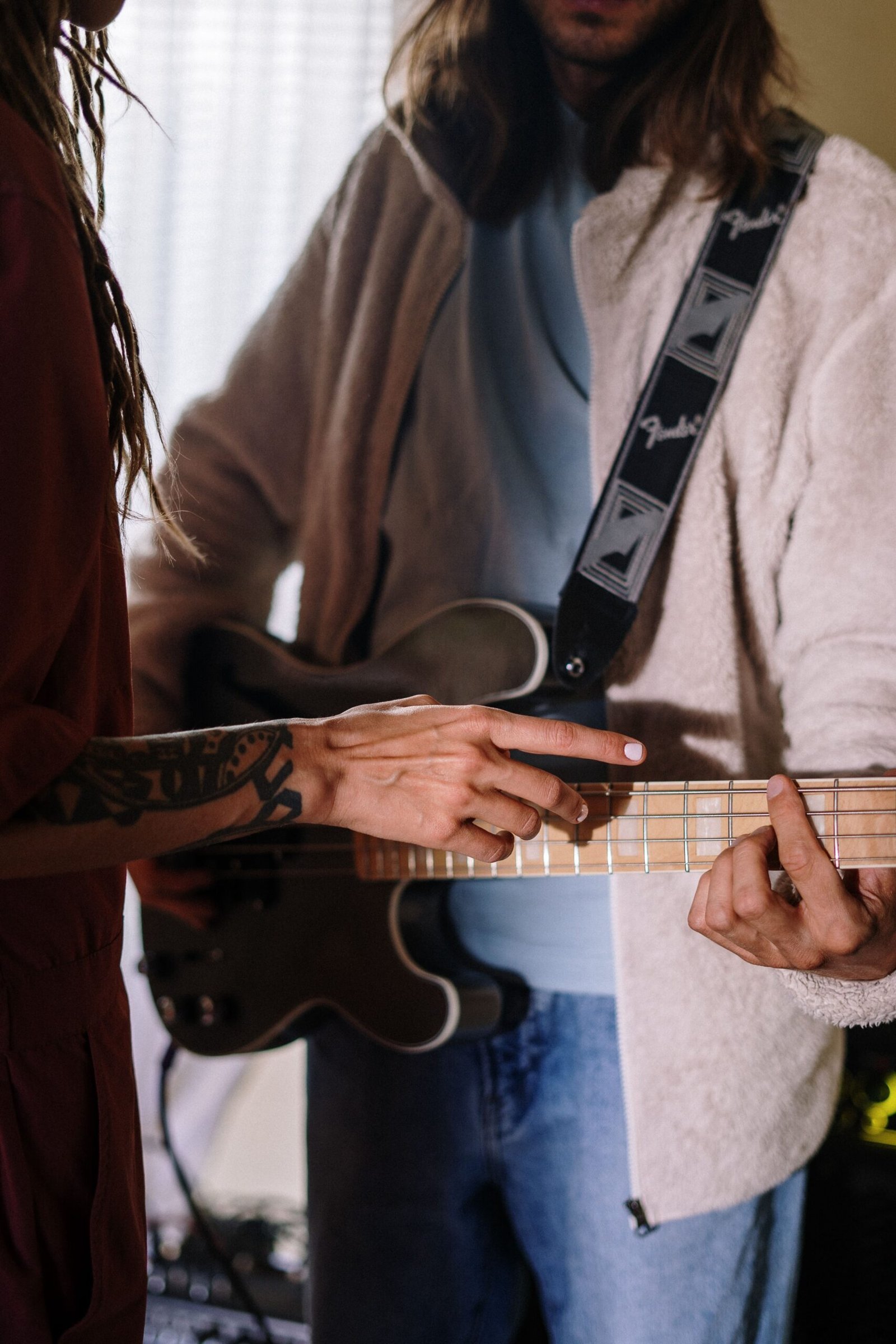 Home Two musicians collaborate in a home studio, focusing on guitar practice with attentive detail.