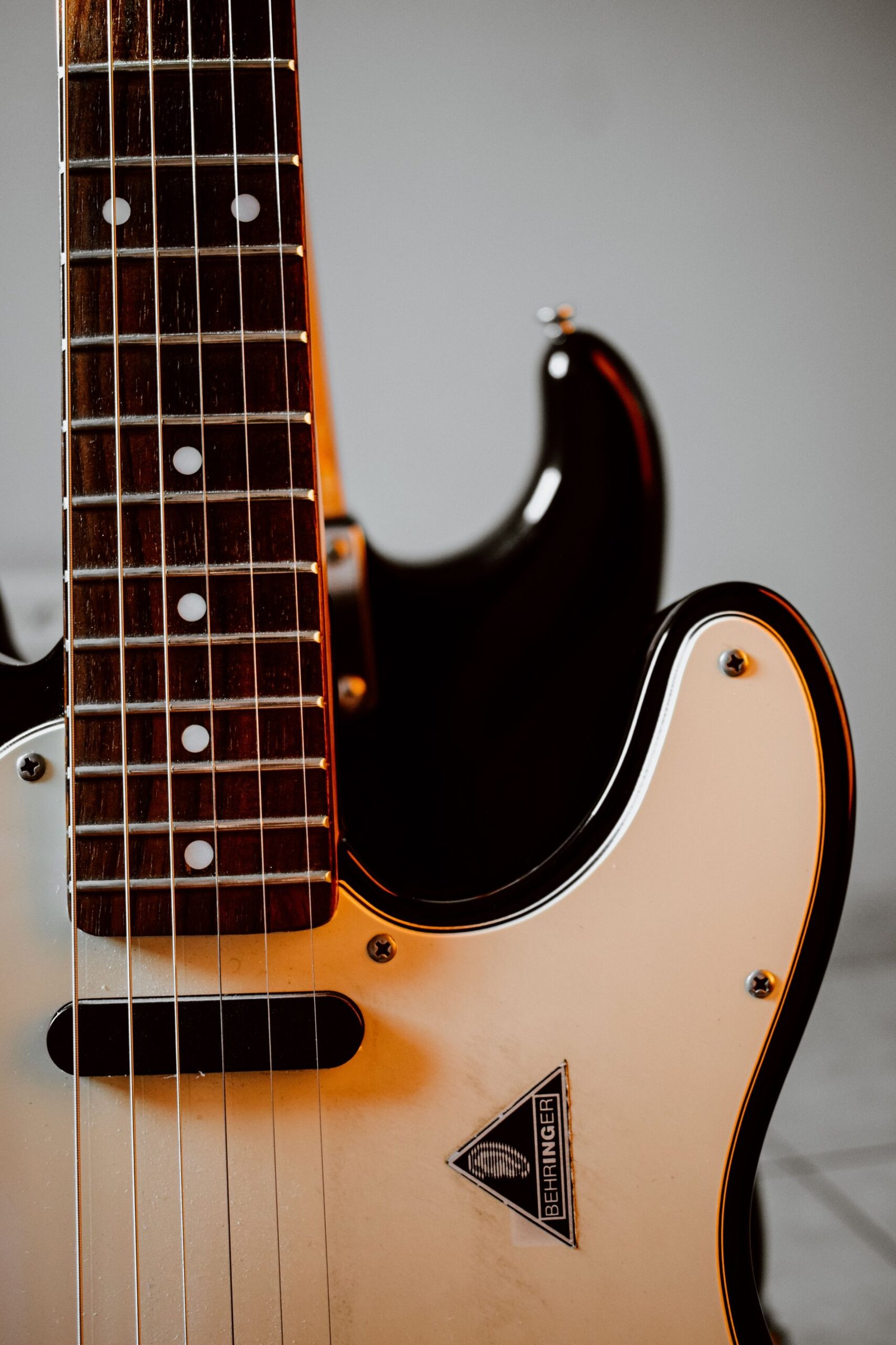 Home Detailed vertical shot of an electric guitar's strings and body.